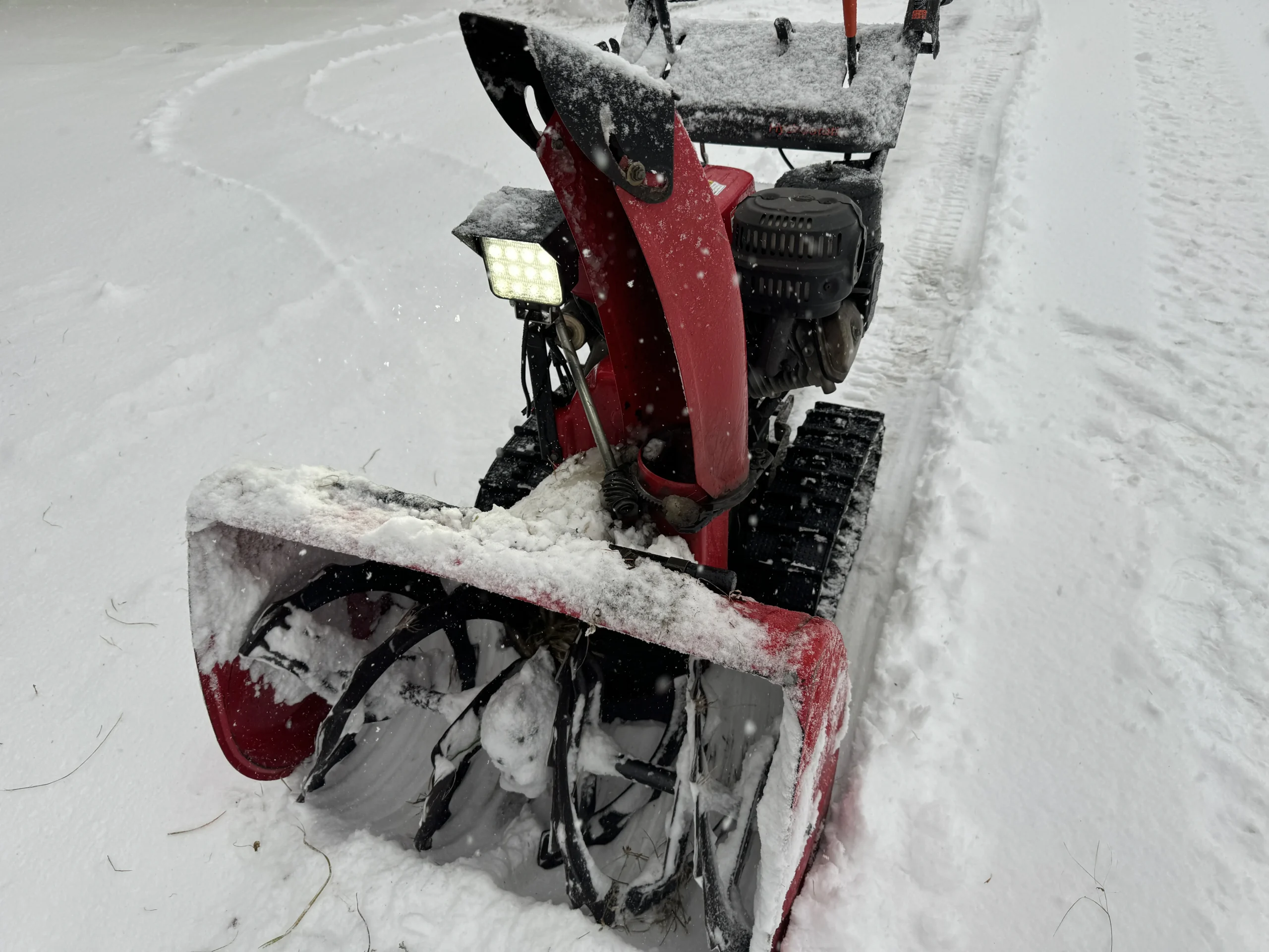 雪の中で稼働する除雪機に取り付けられたNLAセレクトのLED作業灯と防雪ガード